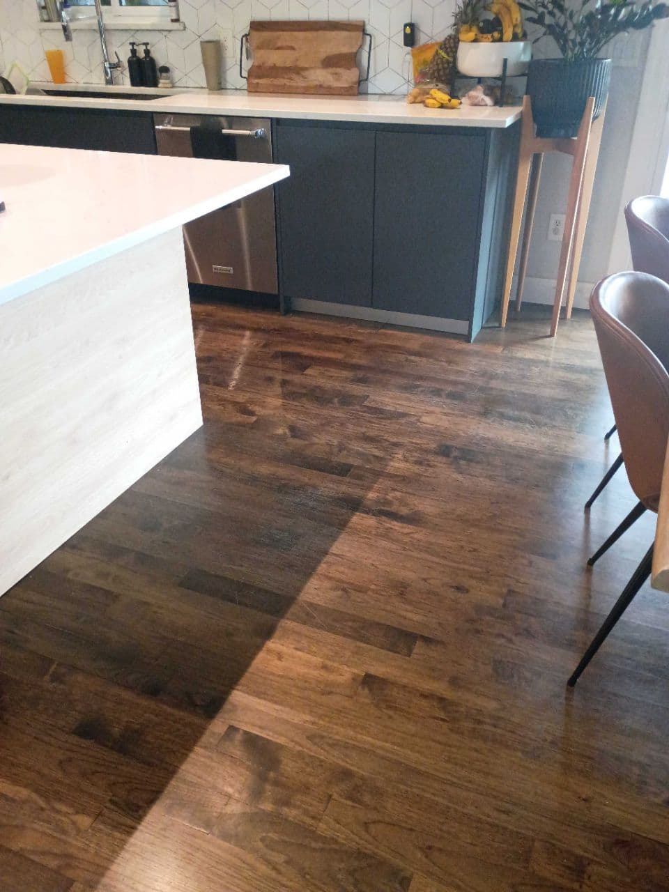 Modern kitchen featuring dark wood floors, a white island, and dark grey lower cabinets.