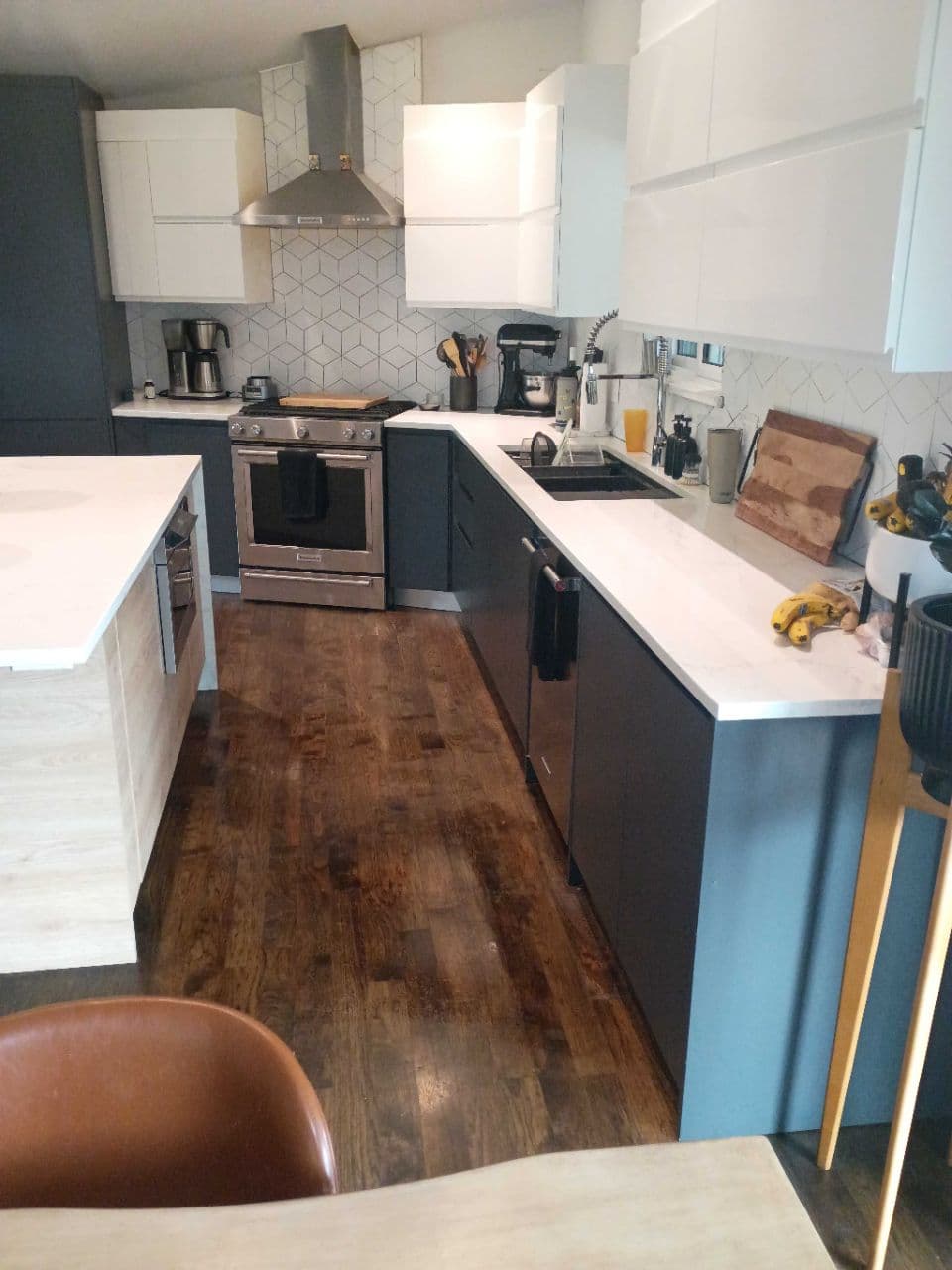 Modern kitchen featuring white and charcoal cabinets, stainless steel appliances, and dark wood flooring.